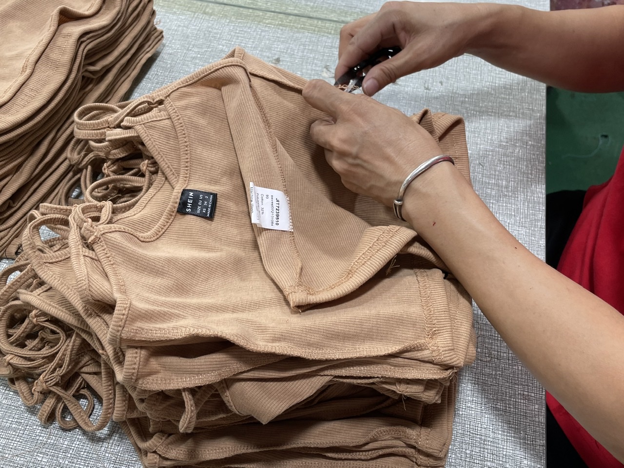 The female workers in the garment factory are picking up the extra thread for the sewn women's sling.